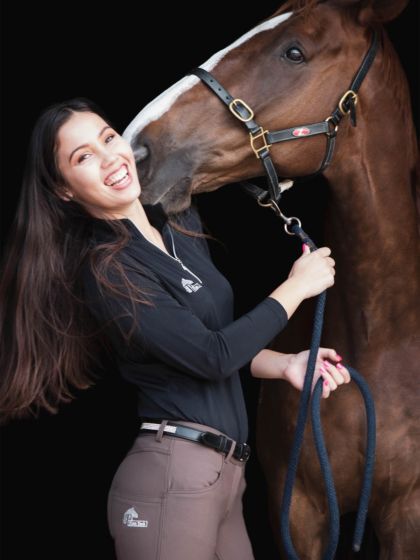 Laughing woman with horse. Shows long sleeve summer riding top and brown bamboo breeches