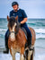 Plus size show shirt shown on woman riding Clydesdale at the beach