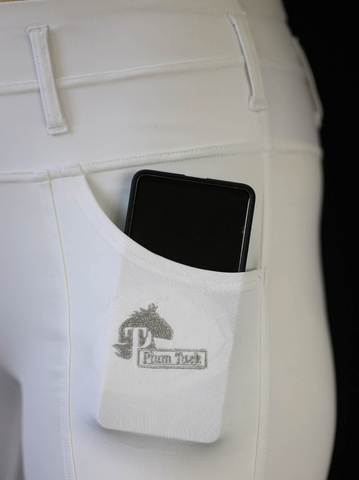 White riding tights close up showing phone in pocket